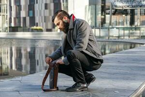 young businessman checking a laptop in the bag in a square of a modern city photo