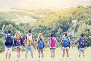 group of hikers in the mountain in single file holding hands photo