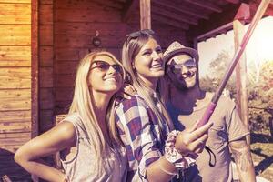 group of smiling friends taking funny selfie with smart phone photo