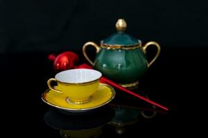 composition of cup and teapot and a symbolic object of christmas on a black background photo