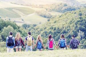 group of hikers in the mountain in single file holding hands photo