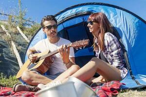 couple of young lovers enjoy playing guitar at the campsite photo