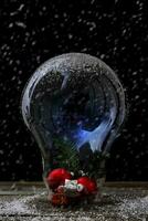 Navidad decoraciones dentro un grande ligero bulbo debajo el nieve foto