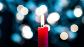 a red candle burns in the foreground in front of a colorful bokeh background photo