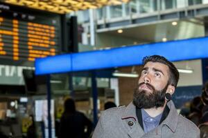 hipster businessman consult the board of timetable trains photo