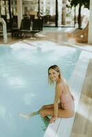 Young woman relaxing by the indoor swimming pool photo