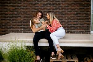 Family with a mother, father and daughter sitting outside on the steps of a front porch of a brick house photo