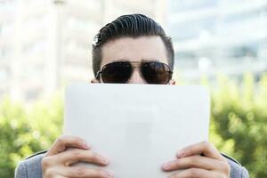 young hipster businessman holding the laptop in front of face photo