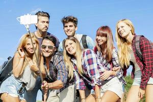 group of friends taking a self portrait with selfie stick photo