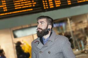 hipster businessman consult the board of timetable trains photo