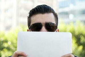 young hipster businessman holding the laptop in front of face photo