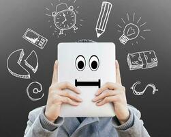 young businessman with tablet in front of his face surrounded of sketches symbols on the wall photo