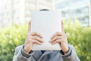 Businessman holding up a tablet in front of his face photo