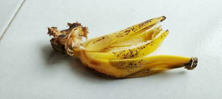 A ripe banana peel lies on the white floor photo