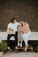 Family with a mother, father and daughter sitting outside on the steps of a front porch of a brick house photo