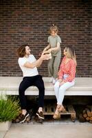 Family with a mother, father and daughter sitting outside on the steps of a front porch of a brick house photo