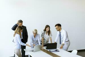 Group of business people with young adults and senior woman colleague on meeting at modern bright office interior photo