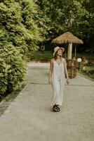 mujer joven con sombrero caminando en el jardín del resort foto