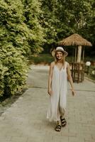 mujer joven con sombrero caminando en el jardín del resort foto