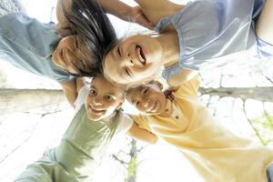 Group of asian and caucasian happy kids huddling, looking down at camera and smiling photo