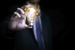 Businessman holding a light bulb creates new ideas. Innovation. Brainstorming. Solutions. And inspiration. Imagination. Creativity. Problem solving. Solution removing obstacles to success in business. photo