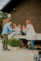 grupo de joven personas y niños comiendo Pizza en el casa patio interior foto