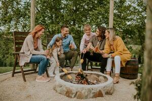 Friends having good time and baking corns in the house backyard photo