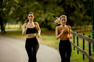 dos bonito joven mujer corriendo en el parque foto