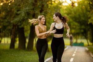 Two pretty young women running on the lane in the park photo