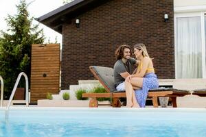 Young couple relaxing by the swimming pool in the house backyard photo