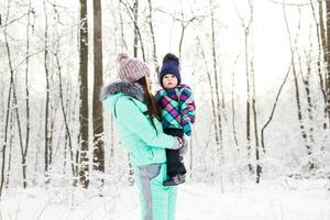 happy family mother and child baby daughter on a winter walk in the woods photo