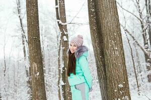 Beautiful young girl walking in winter forest photo