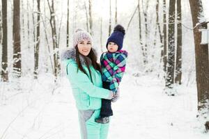 happy family mother and child baby daughter on a winter walk in the woods photo