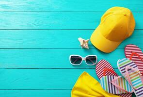 Summer accessories. Cap, sunglasses, flip flops, shell and oranges on blue wooden background. Top view and copy space photo