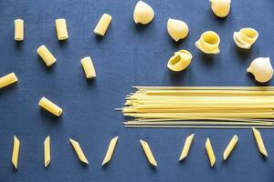 Various types of pasta on the dark background photo