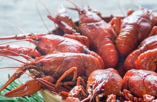 Bowl of boiled crayfish on the wooden table photo