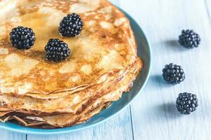 Crepes with blackberries on the wooden table photo