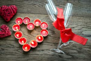 Burning candles in the shape of heart with two flutes photo