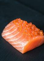 Salmon with red caviar on the black stone board photo