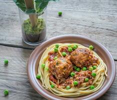 Turkey meatballs with pasta and fresh peas on the wooden table photo