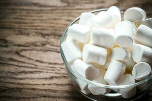 Bowl of marshmallows on the wooden background photo