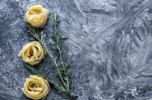 Raw tagliatelle nido on the flour-dusted black wooden background photo