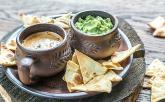 Bowls of guacamole and queso with tortilla chips photo