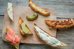 Toasts with different toppings on the wooden board photo