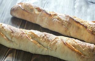 Two baguettes on the wooden background photo