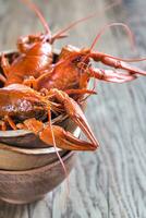 Bowl of boiled crayfish on the wooden table photo