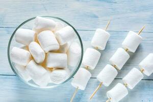 Marshmallow skewers on the wooden background photo