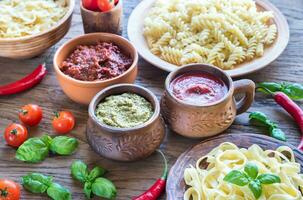 Pasta with different kinds of sauce on the wooden background photo