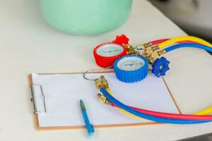 Manifold tool gauge with clipboard checklist on the table, car air conditioning repair concepts photo