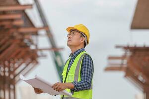 Engineer or architect man in hard hat holding a blueprint at construction site, Construction worker holding plan photo